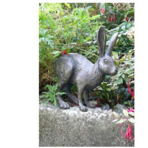 Bronze hare sculpture displayed in a garden setting among plants and natural surroundings